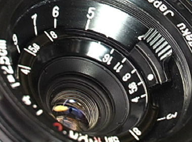 The aperture setting and scales  scales and front lens element of the 25mm f/4.0 old Nikkor RF lens