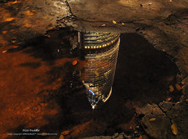Petronas Twin Towers in reflection of water puddle after the rain storm
